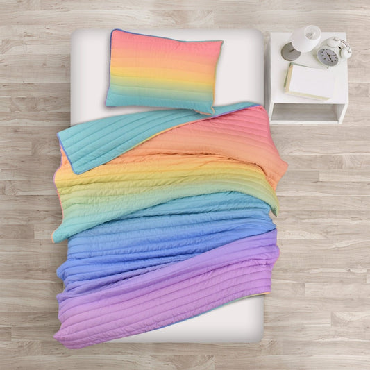 Colorful gradient quilt and pillow on a bed with a wooden floor background