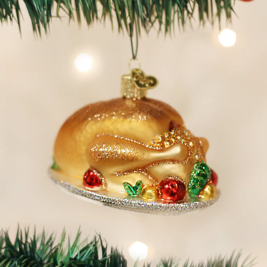 Turkey Platter ornament from Old World Christmas. A golden-brown roast turkey rests on a silver-toned platter, surrounded by colorful garnish details and finished with glitter accents.