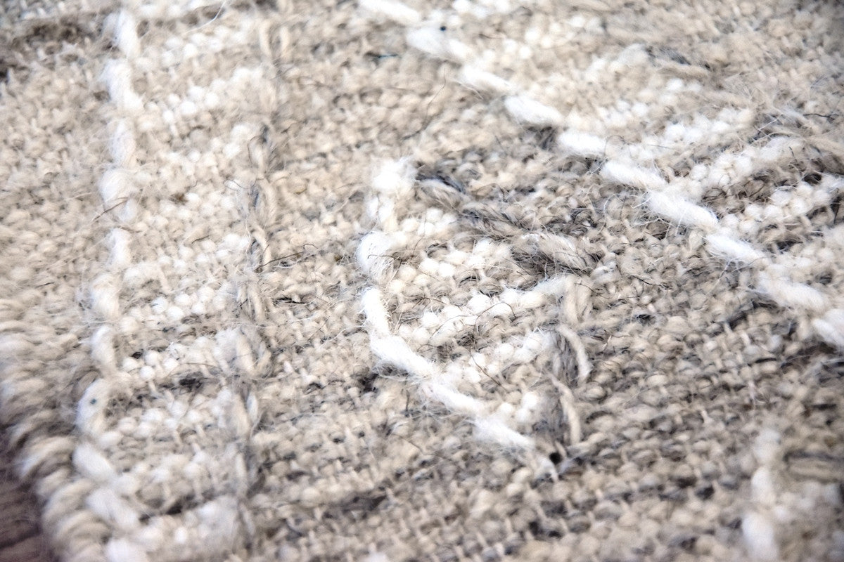 Close-up of a textured beige and white rug with a geometric pattern.