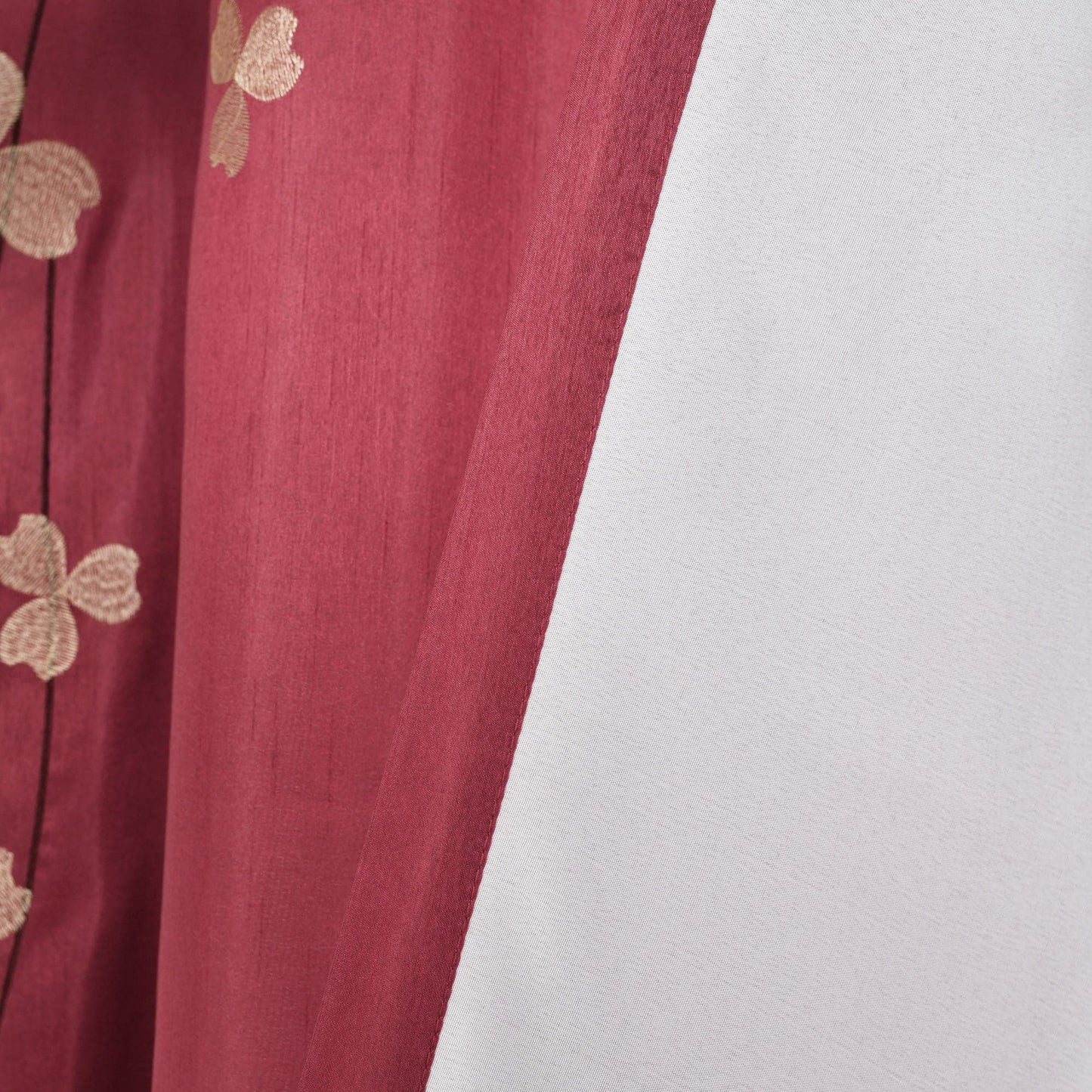Red fabric with gold floral patterns on a white background