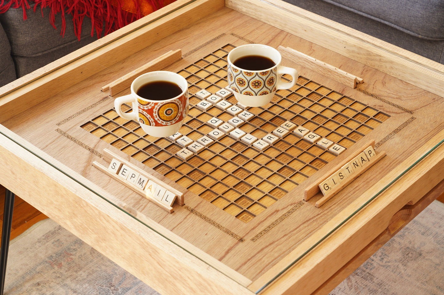 Wooden table with a scrabble board and two cups of coffee.