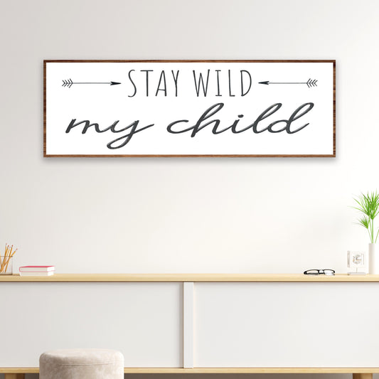 Decorative sign with 'Stay Wild my child' text on a wall above a shelf.