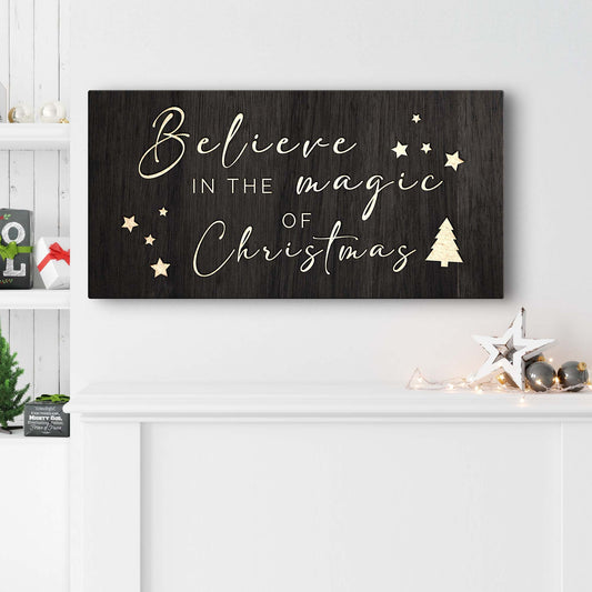 Decorative sign with 'Believe in the magic of Christmas' text on a wooden background, displayed in a festive setting.
