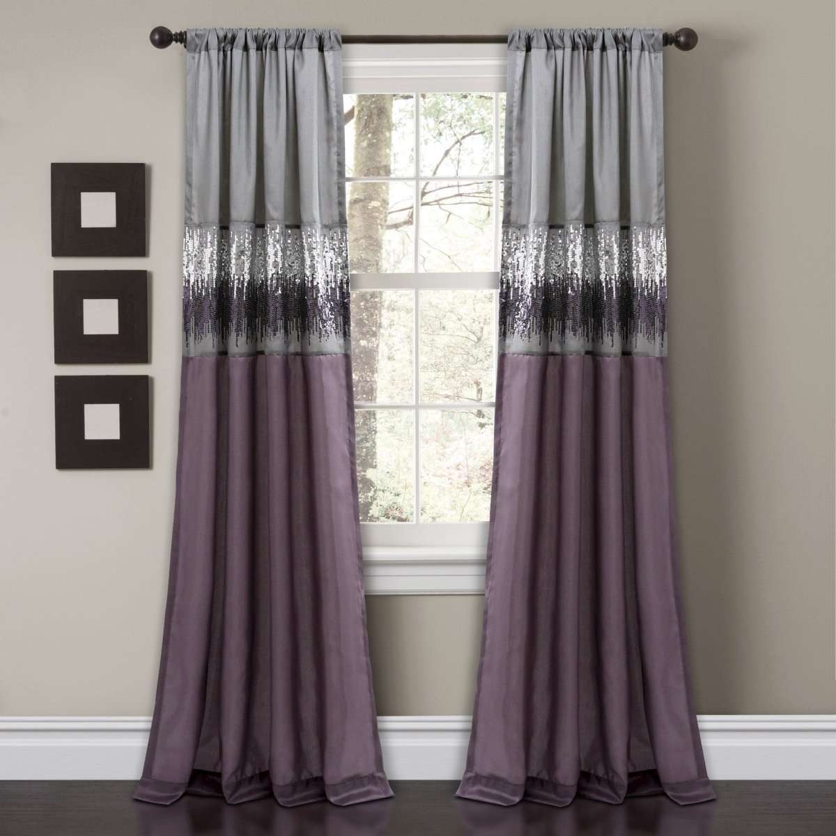 Pair of purple and gray curtains hanging in front of a window with decorative wall art above. Shimmery and sparkly sequins curtain panel.