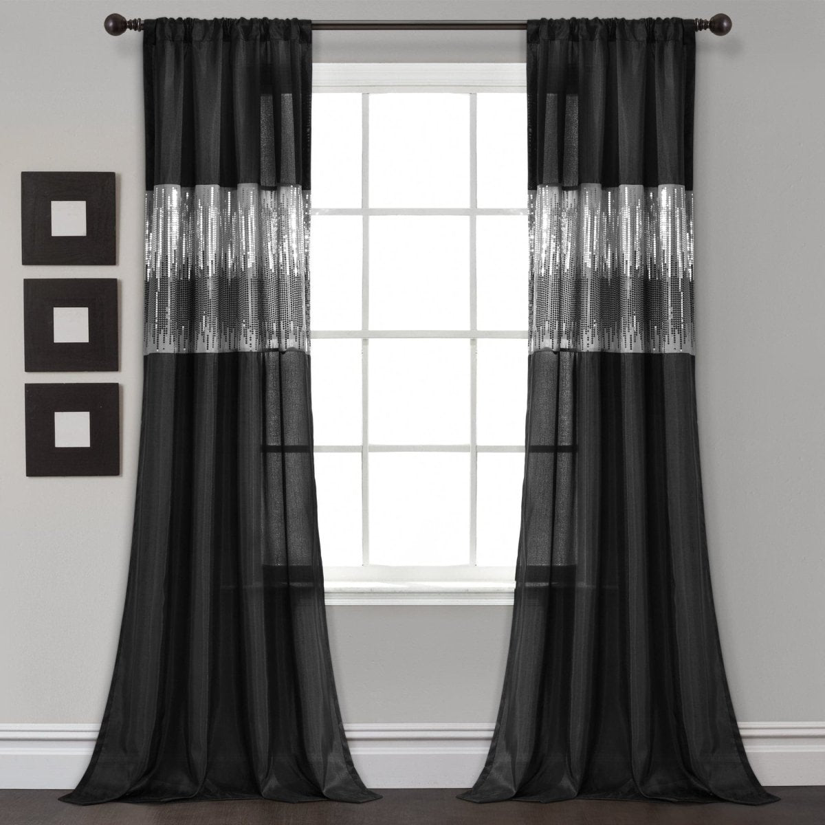 Black curtains with silver accents hanging in front of a window. Shimmery and sparkly sequins curtain panel.