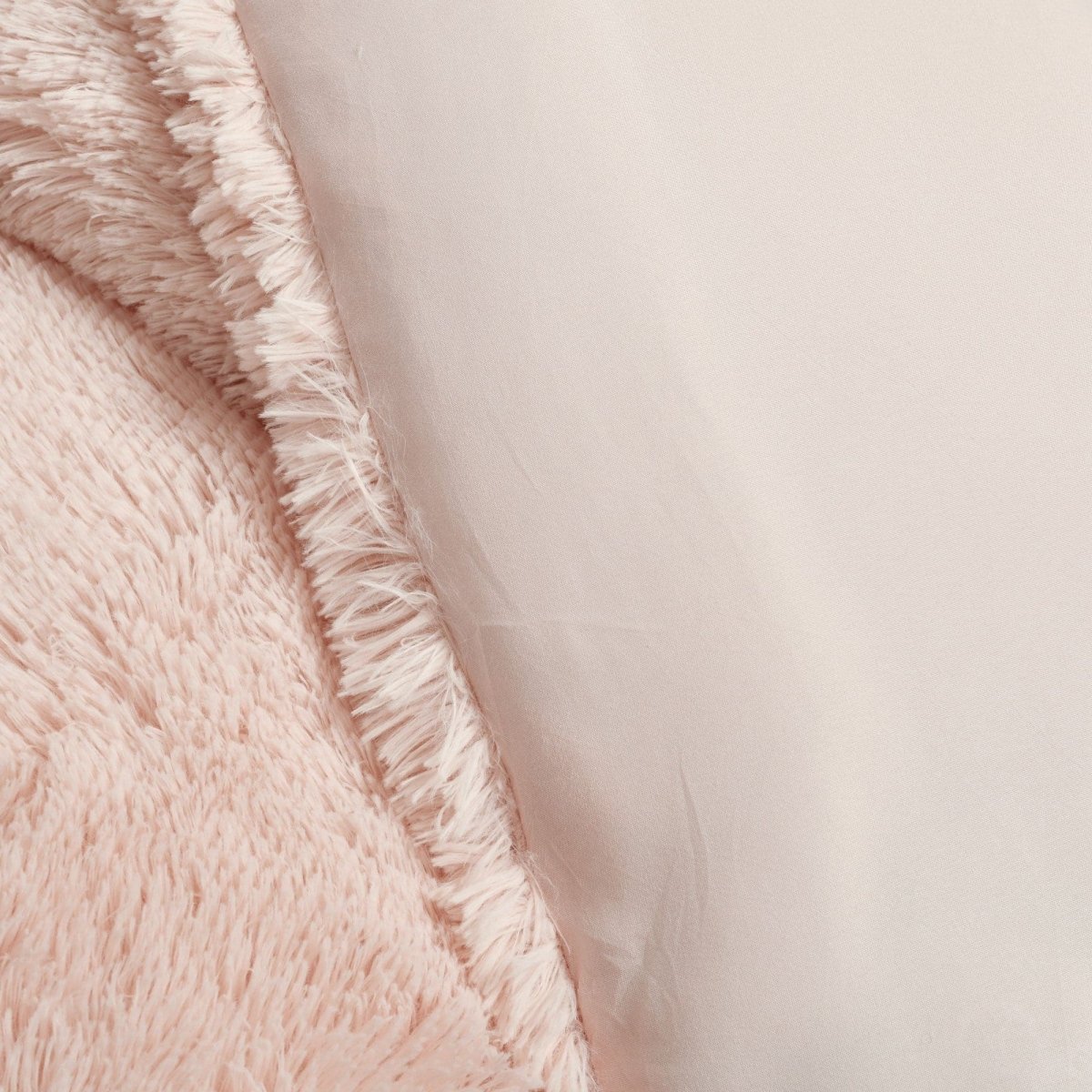 Close-up of a fluffy pink blanket with frayed edges on a light beige background. Faux fur bedding bed set.