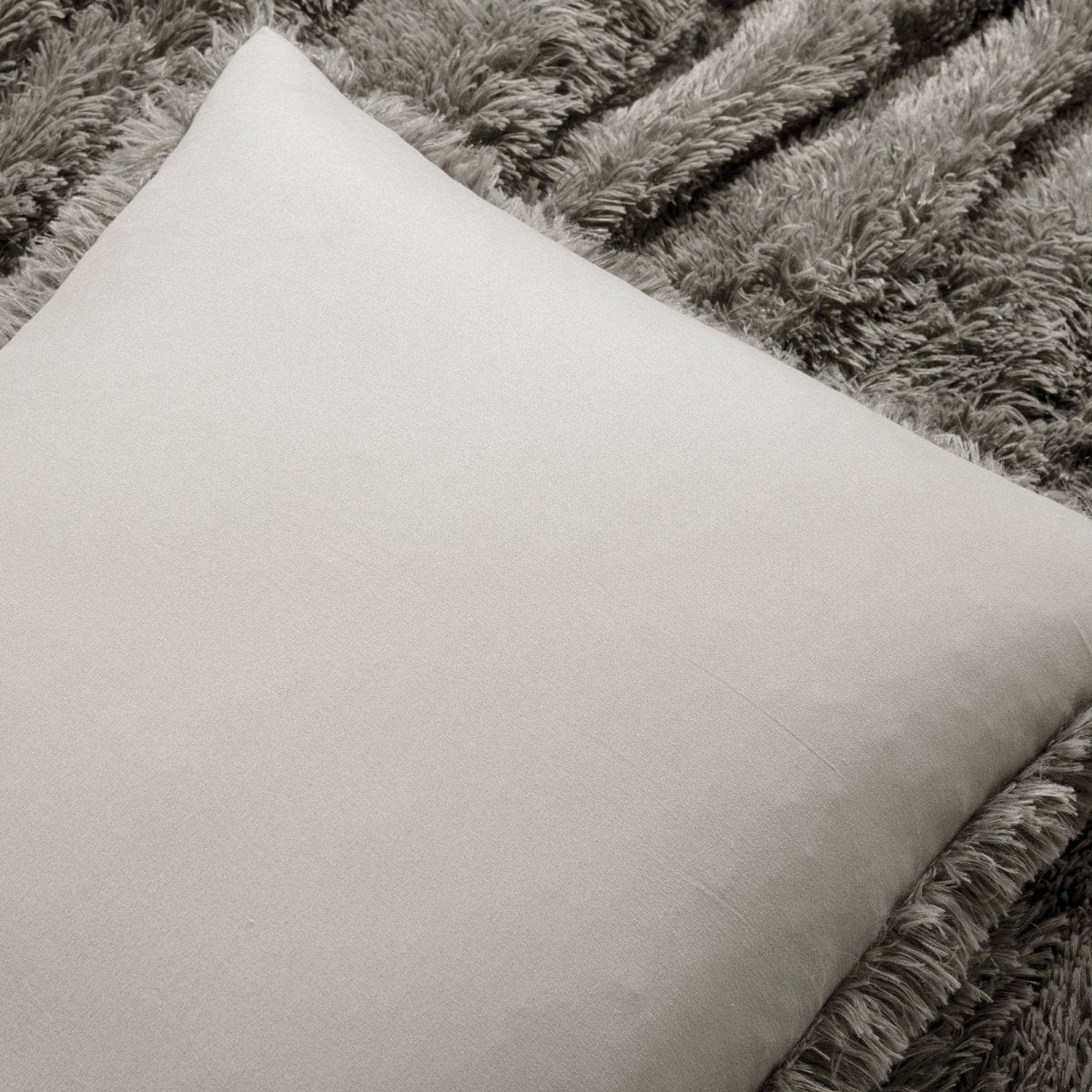 Beige pillow on a textured gray blanket. Faux fur bedding bed set.