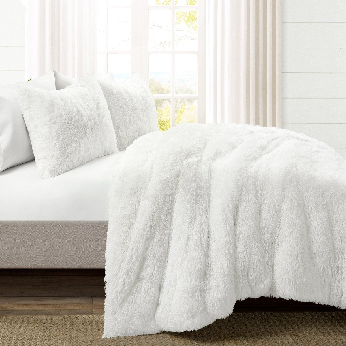 White fluffy comforter on a bed in a bright room with light-colored walls. Faux fur bedding