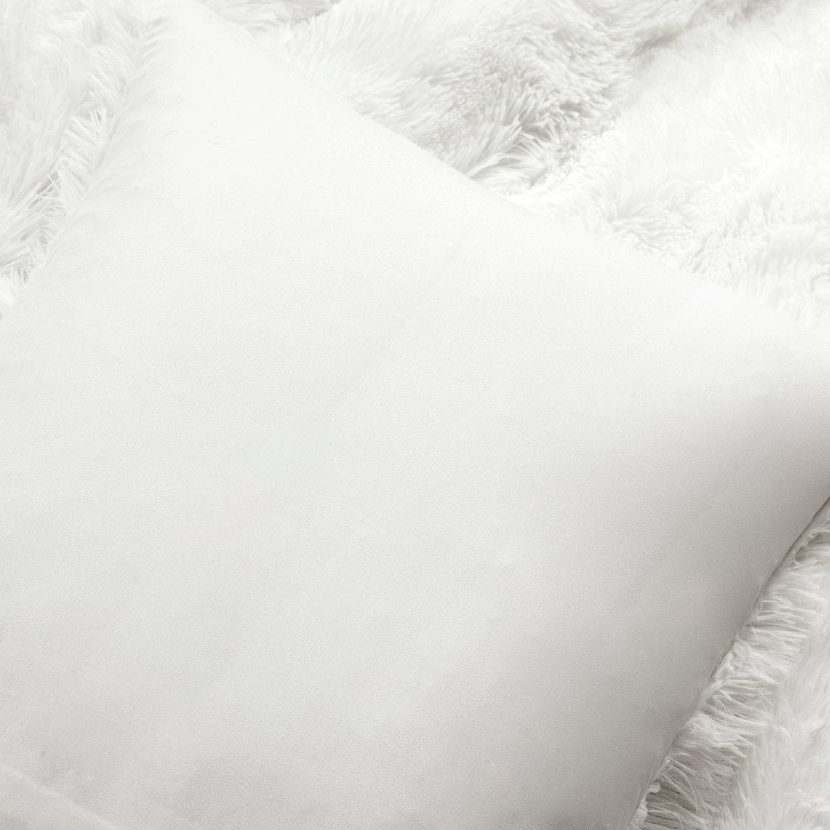 Close-up of a fluffy white pillow with textured edges. Faux fur bedding
