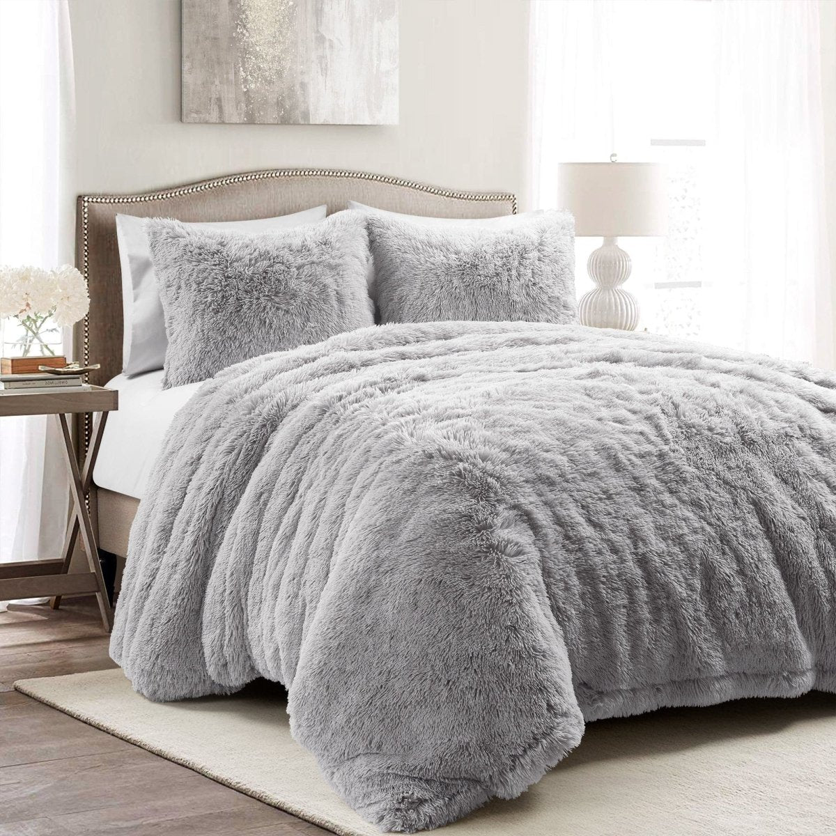 Gray fuzzy comforter set on a bed in a bedroom setting.White textured comforter on a bed in a bright bedroom setting. Faux fur bedding