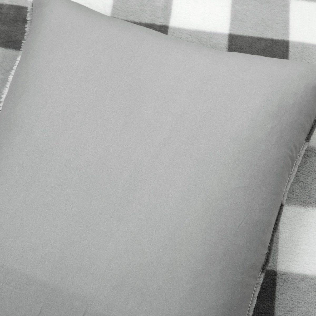 Gray pillow on a checkered fabric background. Faux fur checkered comforter bed set