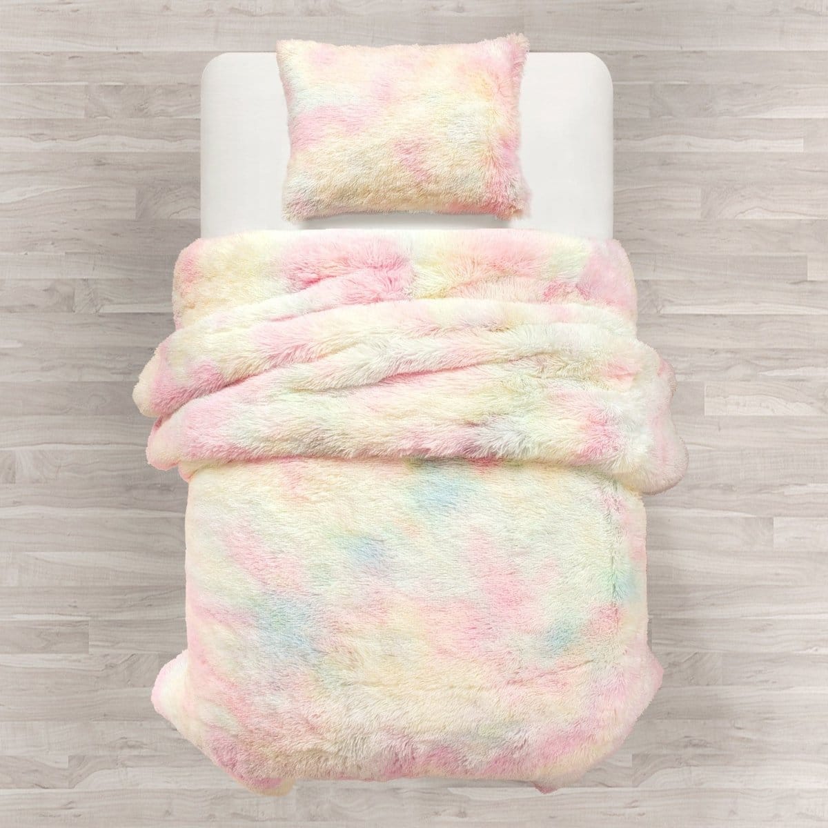 Pastel tie-dye comforter and pillow on a bed with wooden floor background