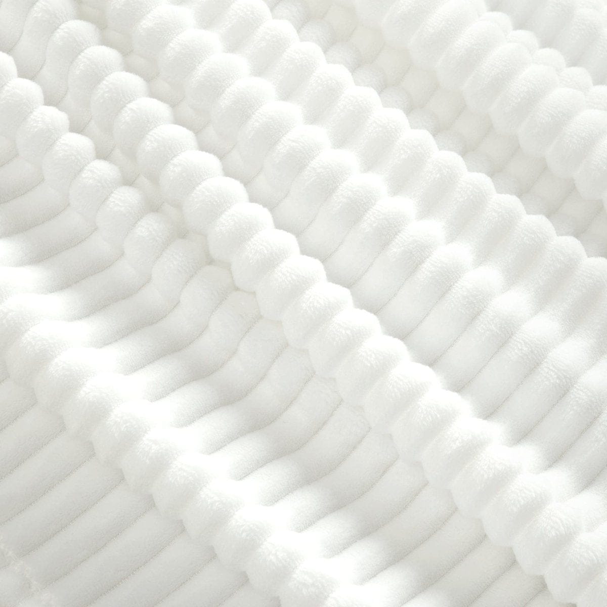 Close-up of white textured fabric with a subtle pattern.White textured throw blanket, faux fur blanket