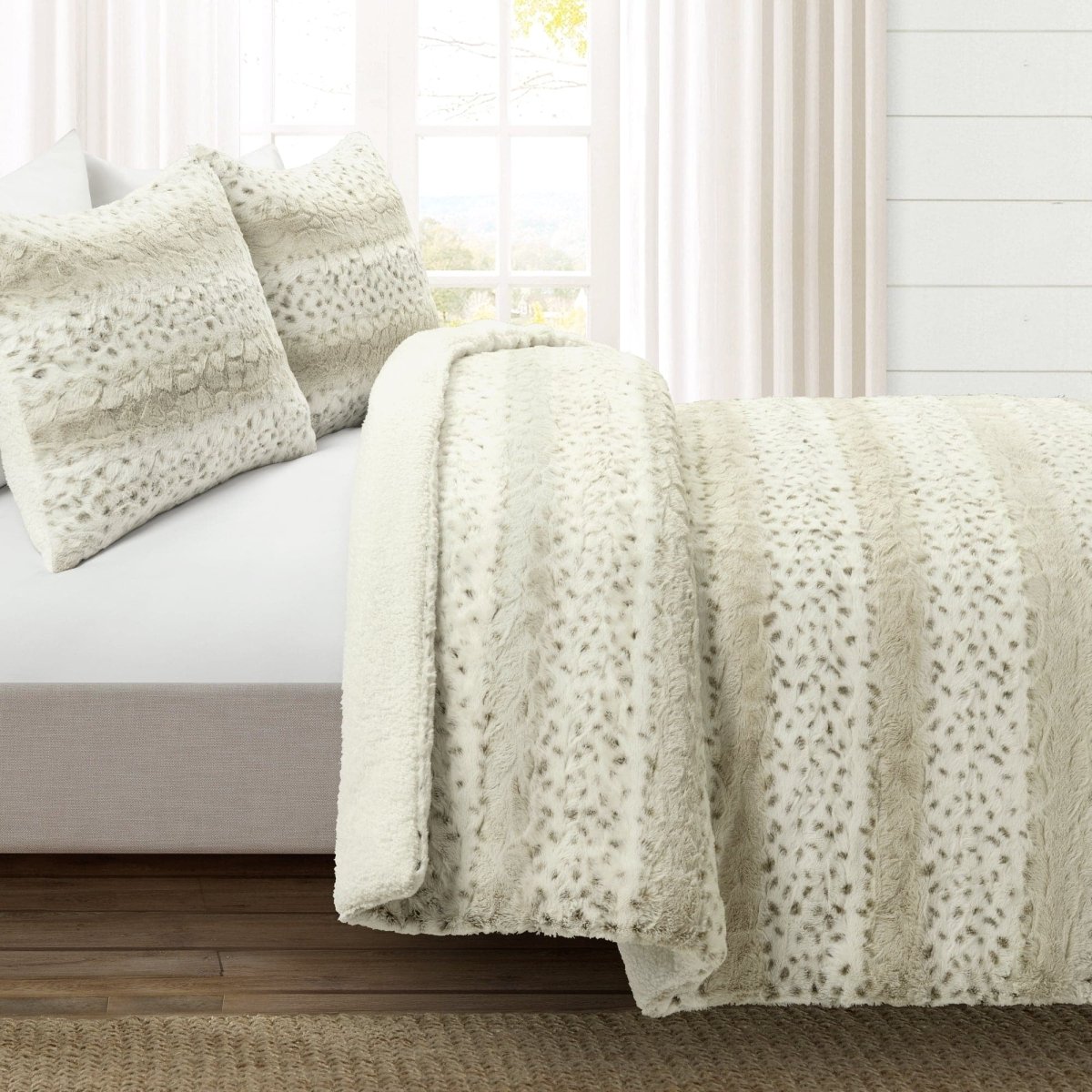 Neatly made bed with textured beige blanket and pillows in a bright bedroom.Leopard faux fur in color block stripe bedding