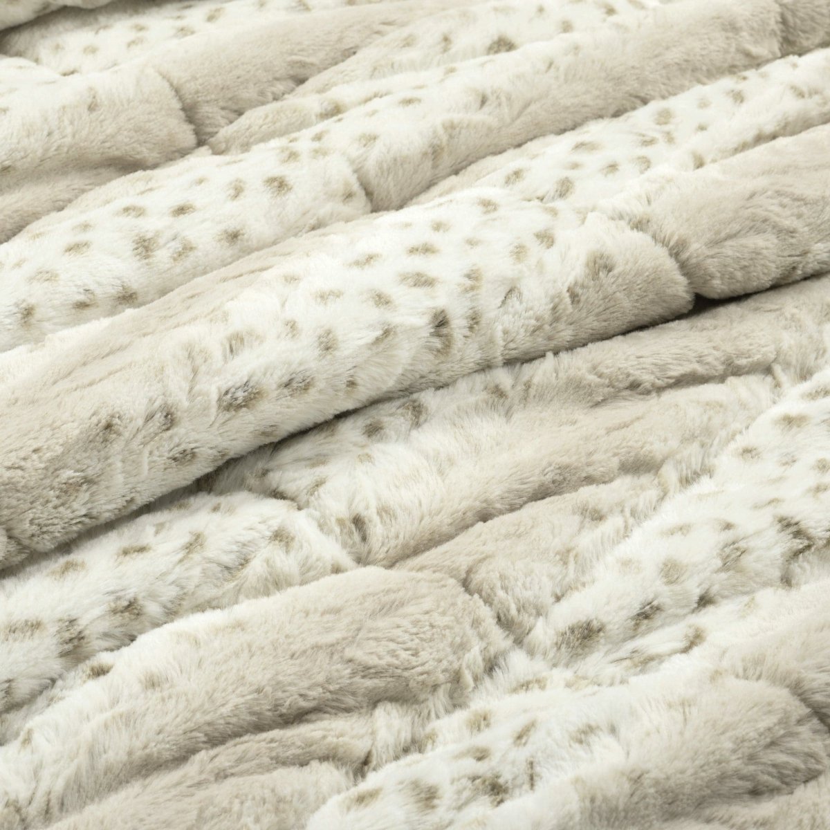 Close-up of a textured beige fabric with a soft, plush surface.Leopard faux fur in color block stripe bed set