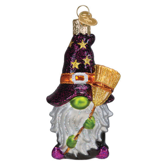 Decorative gnome ornament with witch hat, broom, and green eye on a white background