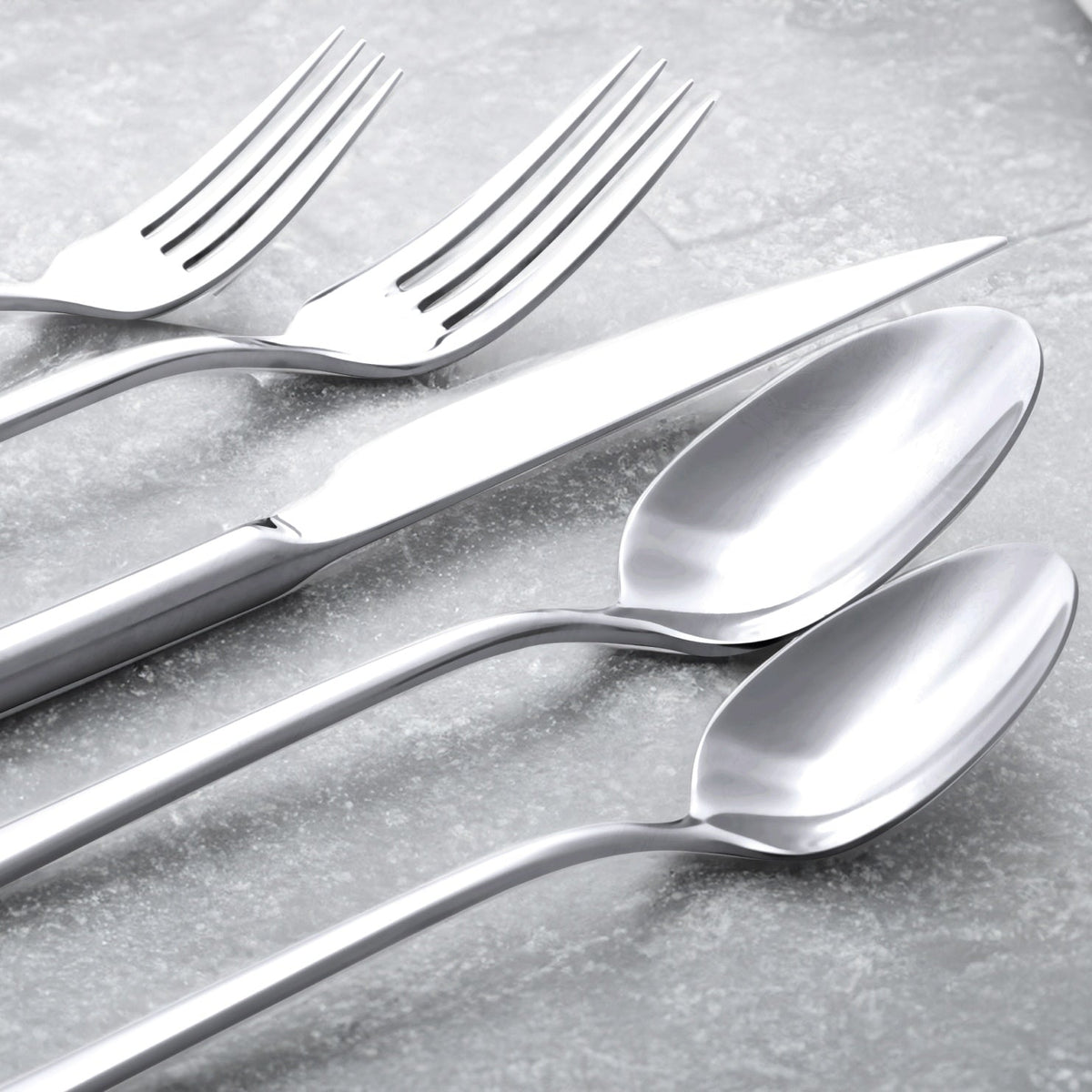 Set of silver forks and spoons on a gray surface