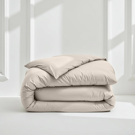 Beige comforter folded neatly on a white surface with a light gray wall background