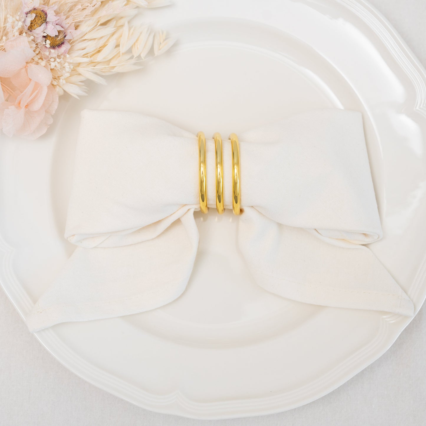Gold ring on a white plate with a white napkin and floral decoration.