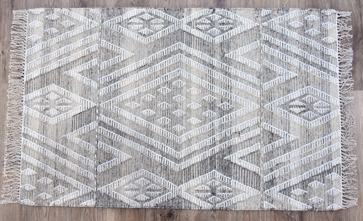 Geometric patterned rug with fringes on a wooden floor