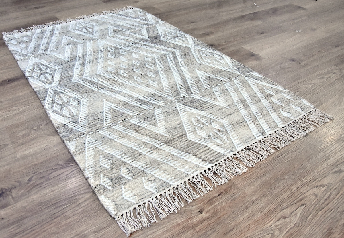 Geometric patterned rug with fringes on a wooden floor