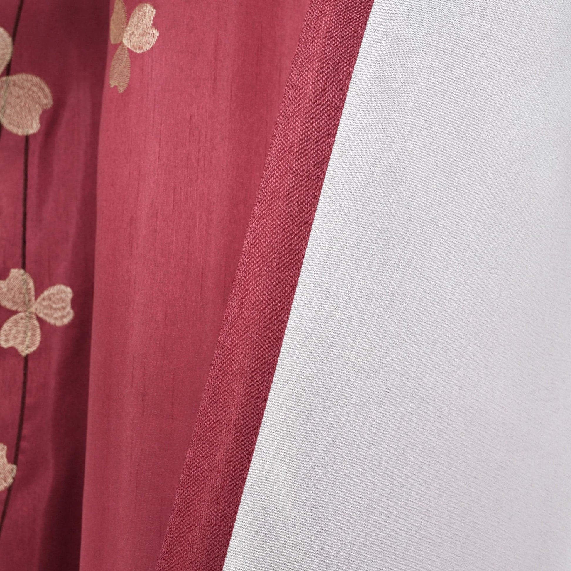 Red fabric with gold floral patterns on a white background