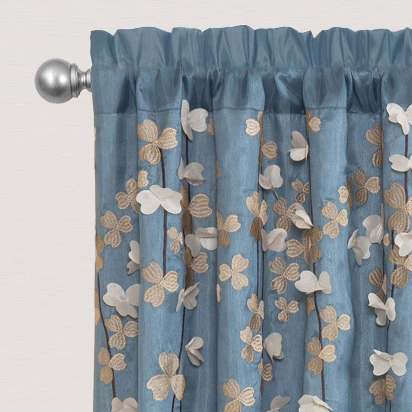 Blue floral drop embroidered curtain with a decorative rod on a light gray background