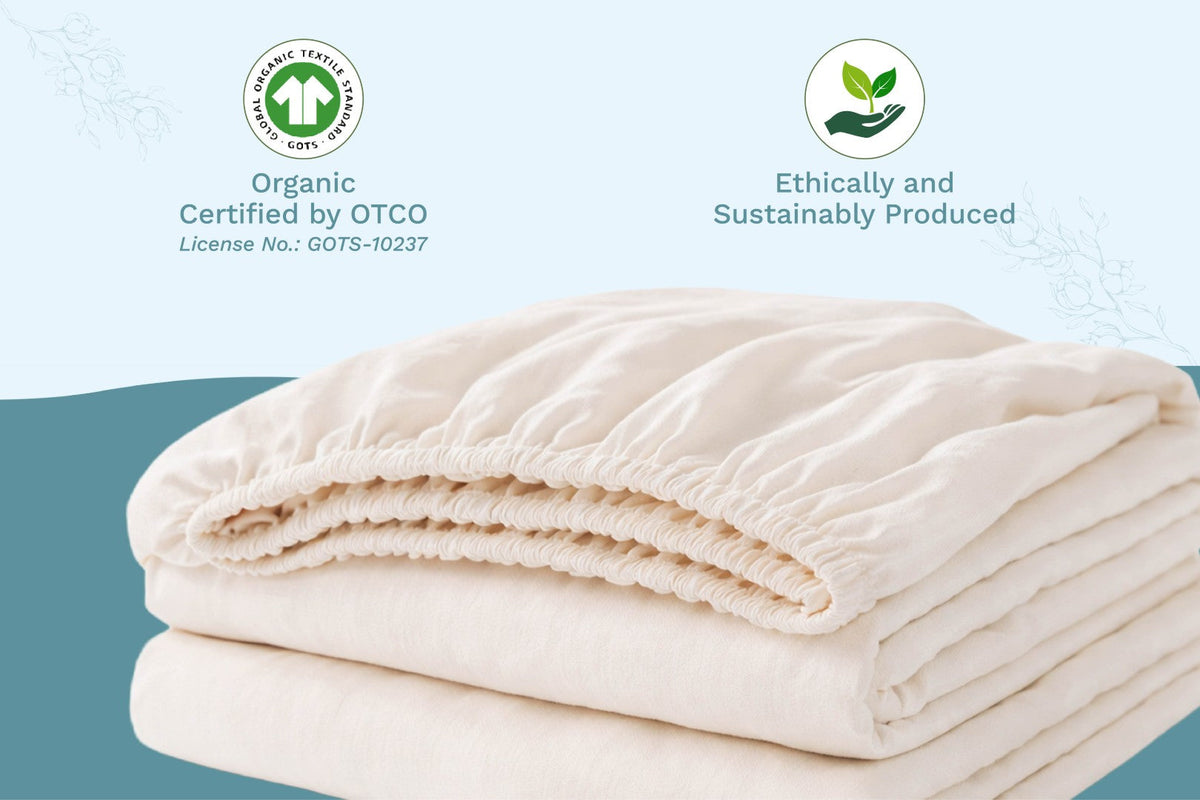 Folded beige blanket with organic certification logos on a light blue background