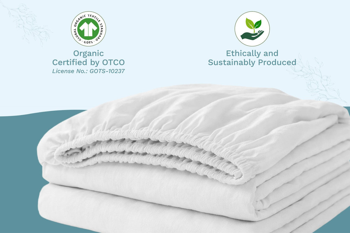 Folded white blanket with organic certification logos on a light blue background