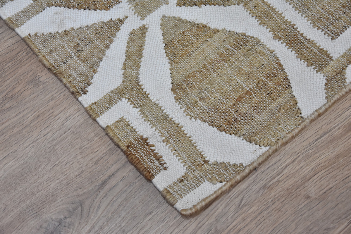 Close-up of a textured area rug with geometric pattern on a wooden floor.