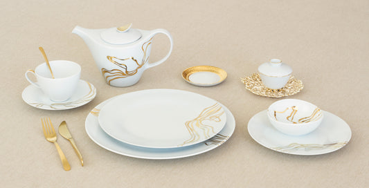 Ceramic tableware set with gold accents on a beige background