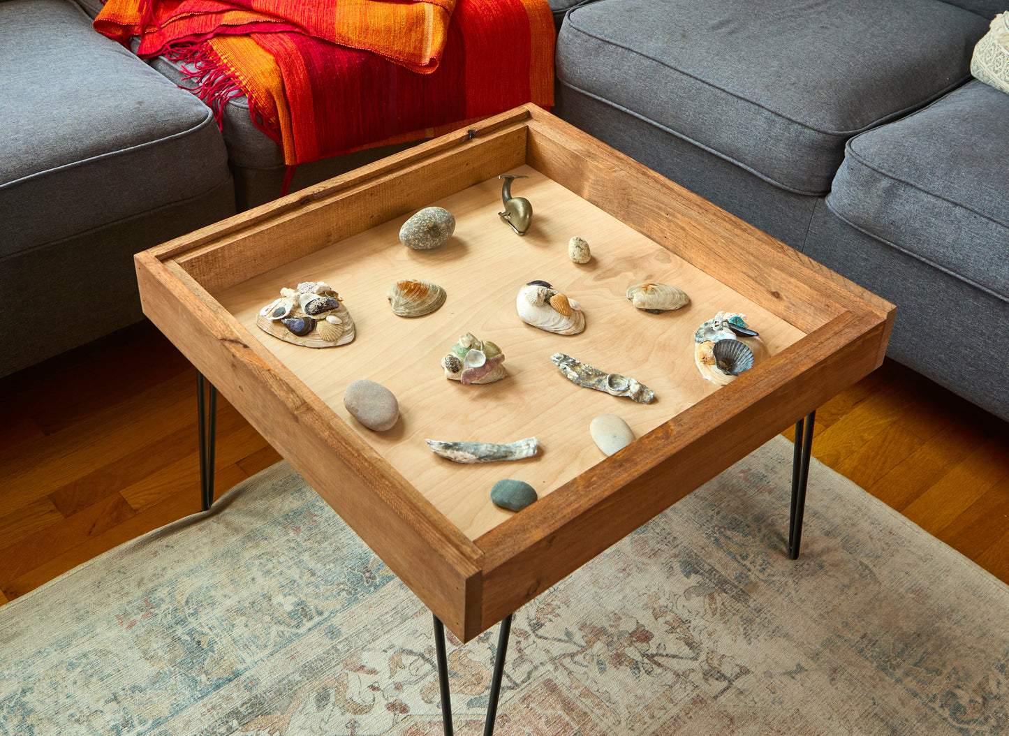 Wooden coffee table with decorative stones on a living room rug