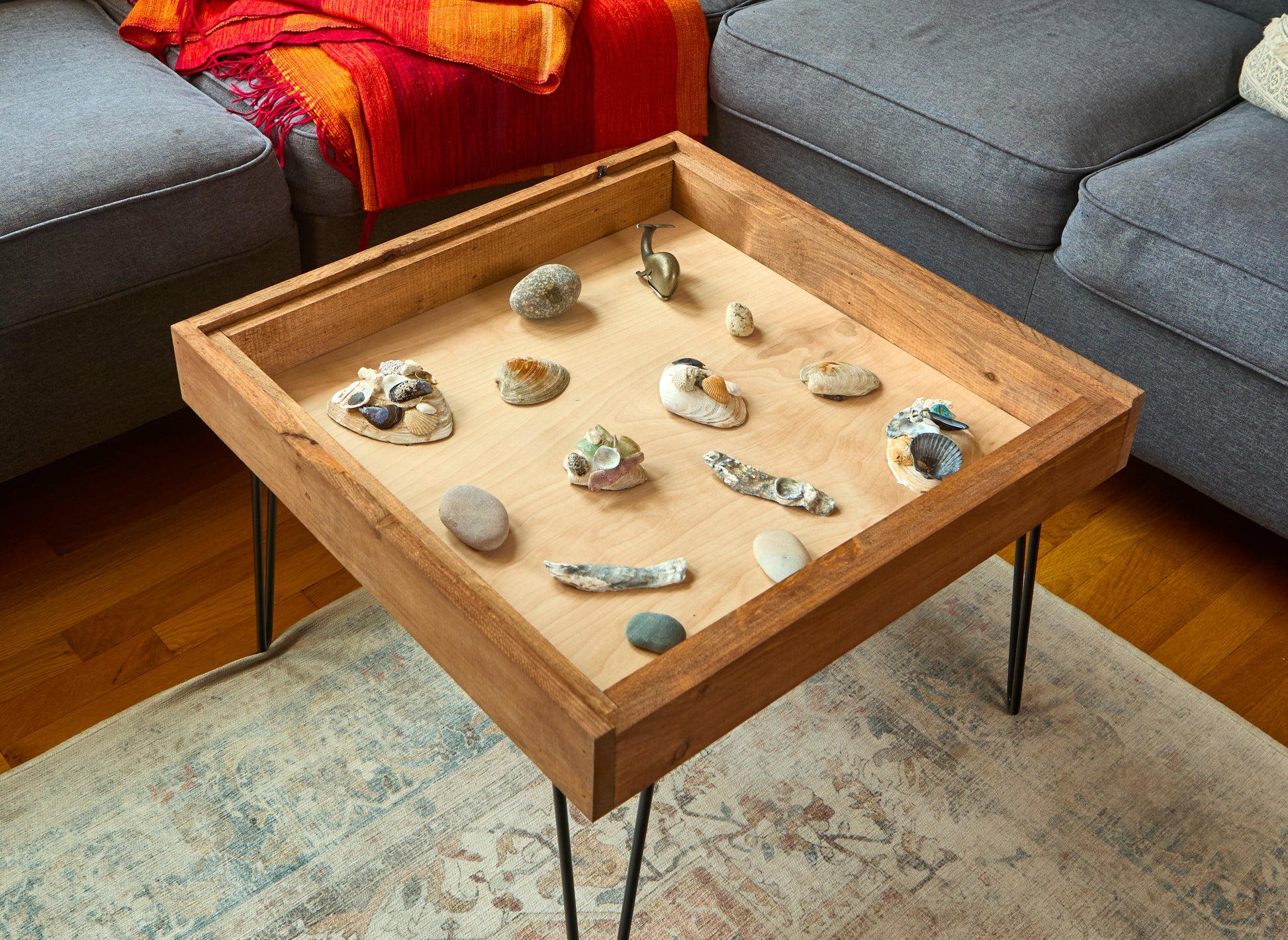 Wooden coffee table with decorative stones on a living room rug