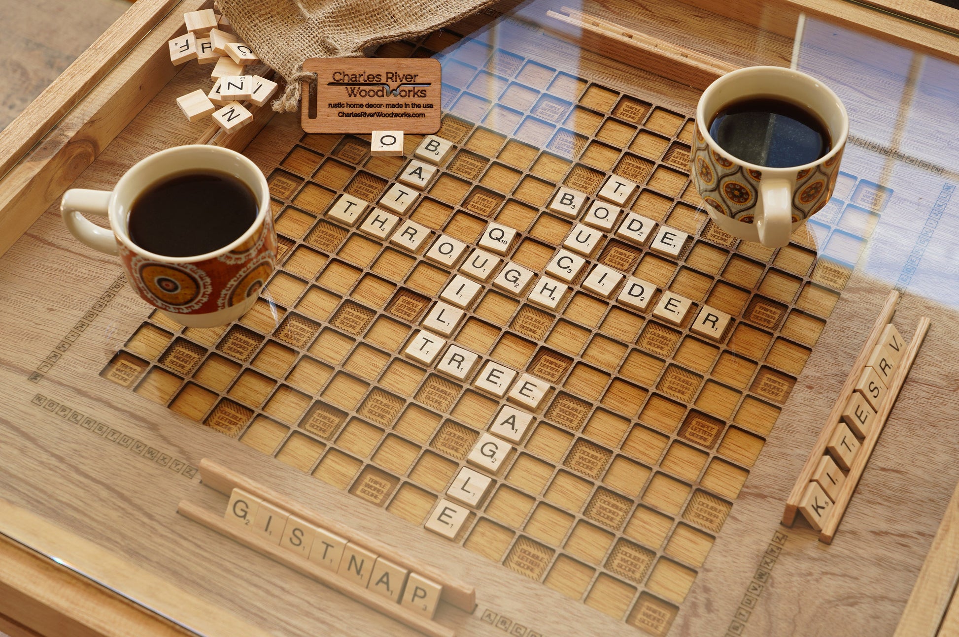 Wooden scrabble board with tiles and two coffee cups on a wooden tray.