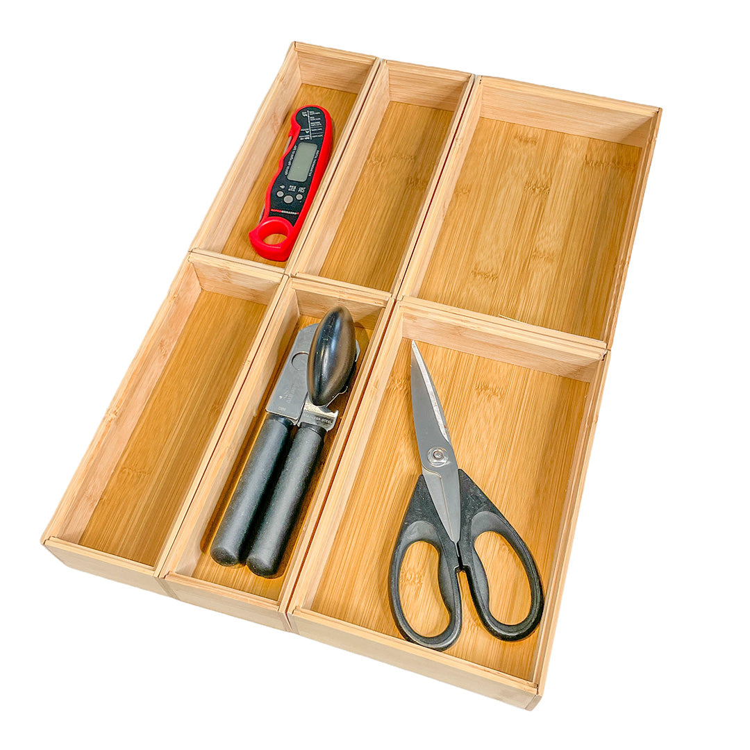 Wooden kitchen organizer with compartments holding a digital thermometer, garlic press, and scissors.