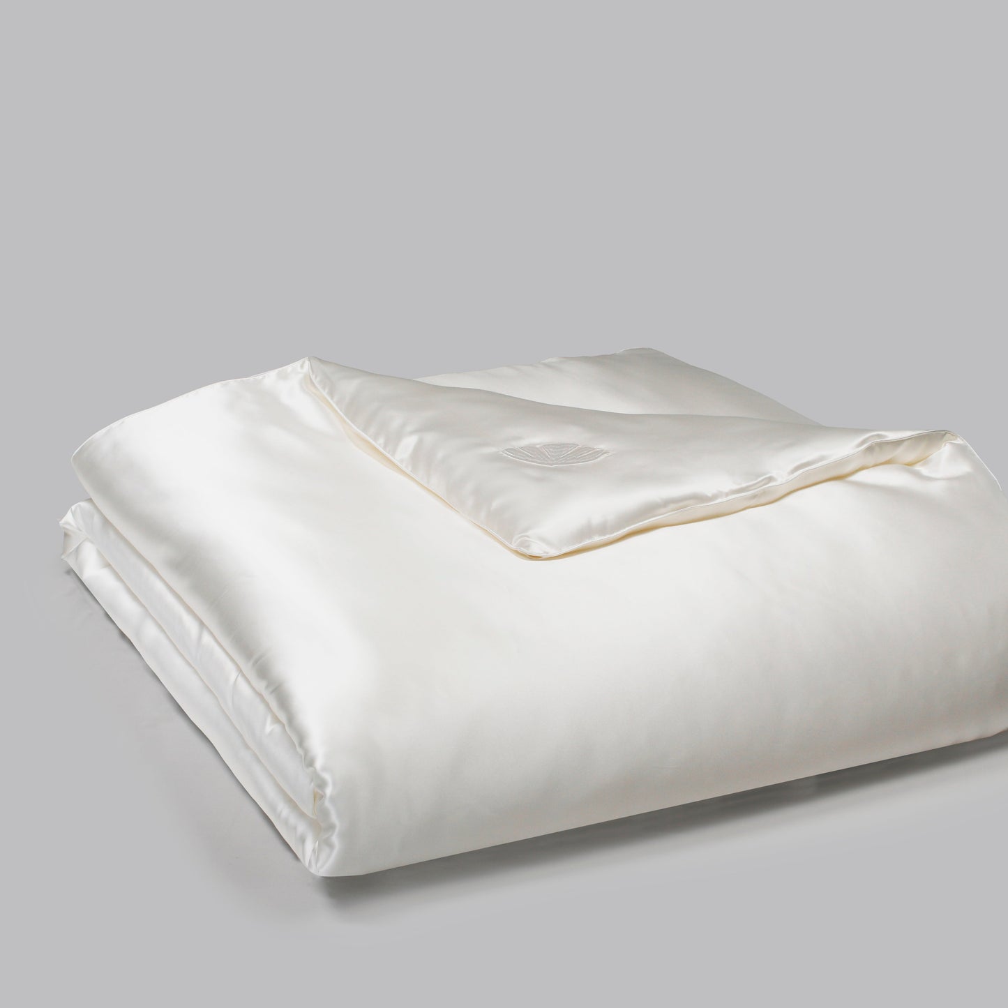 White silk comforter folded on a gray background