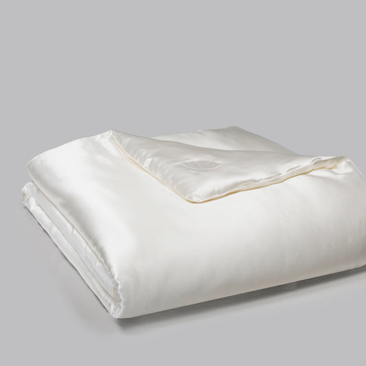 White silk comforter folded on a gray background