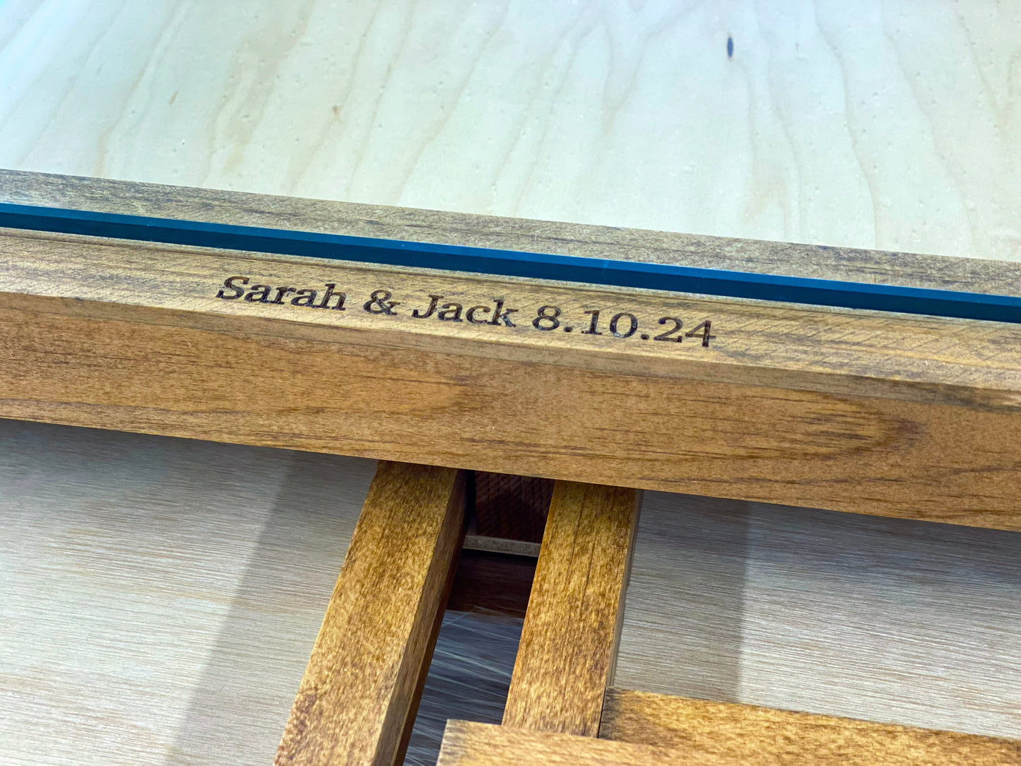 Wooden bench with engraved text 'Sarah & Jack 8.10.24' on a light wooden surface.