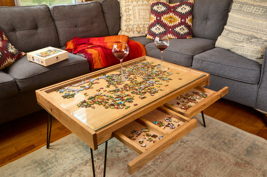 Wooden coffee table with puzzle pieces and drawers, placed on a gray sofa.