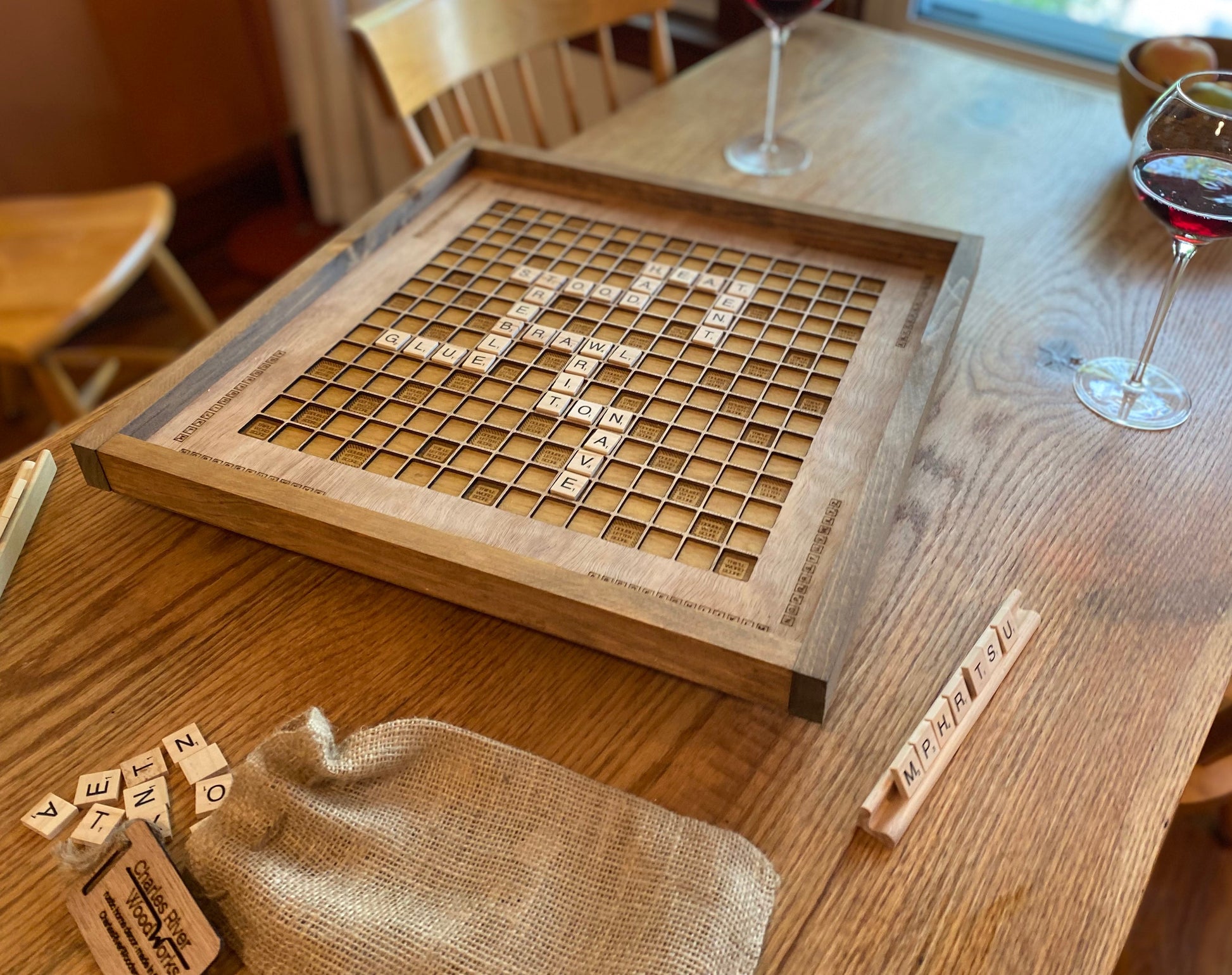 Wooden scrabble board on a table with wine glasses in the background