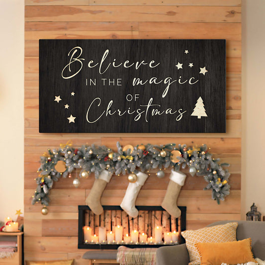 Decorative sign with 'Believe in the magic of Christmas' above a fireplace with stockings and candles.