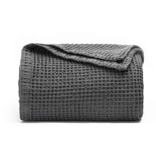 A dark gray waffle-weave blanket, folded with one corner folded over, displayed on a clean white background.
