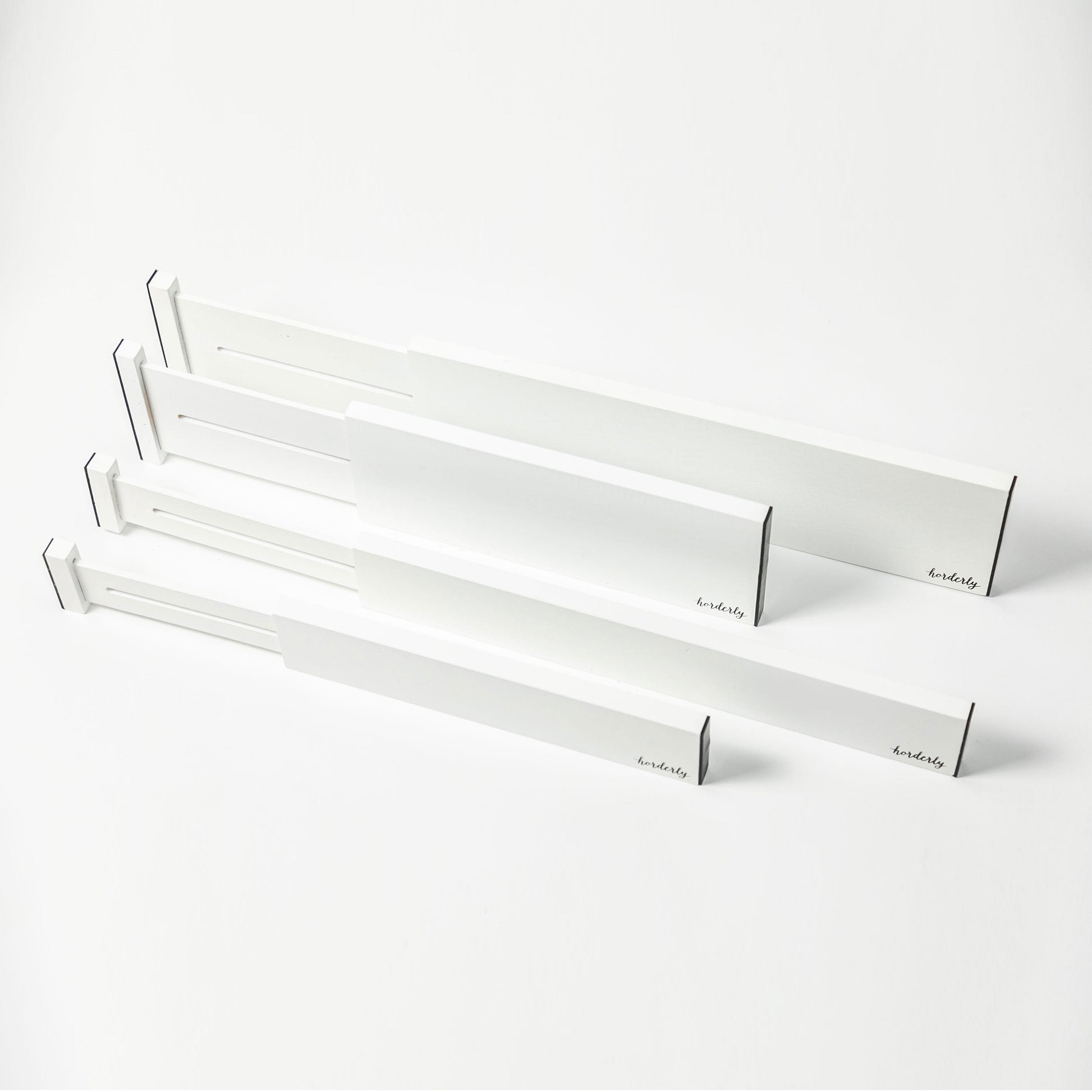 Set of white rectangular expandable bamboo drawer separators with horderly branding on a white background