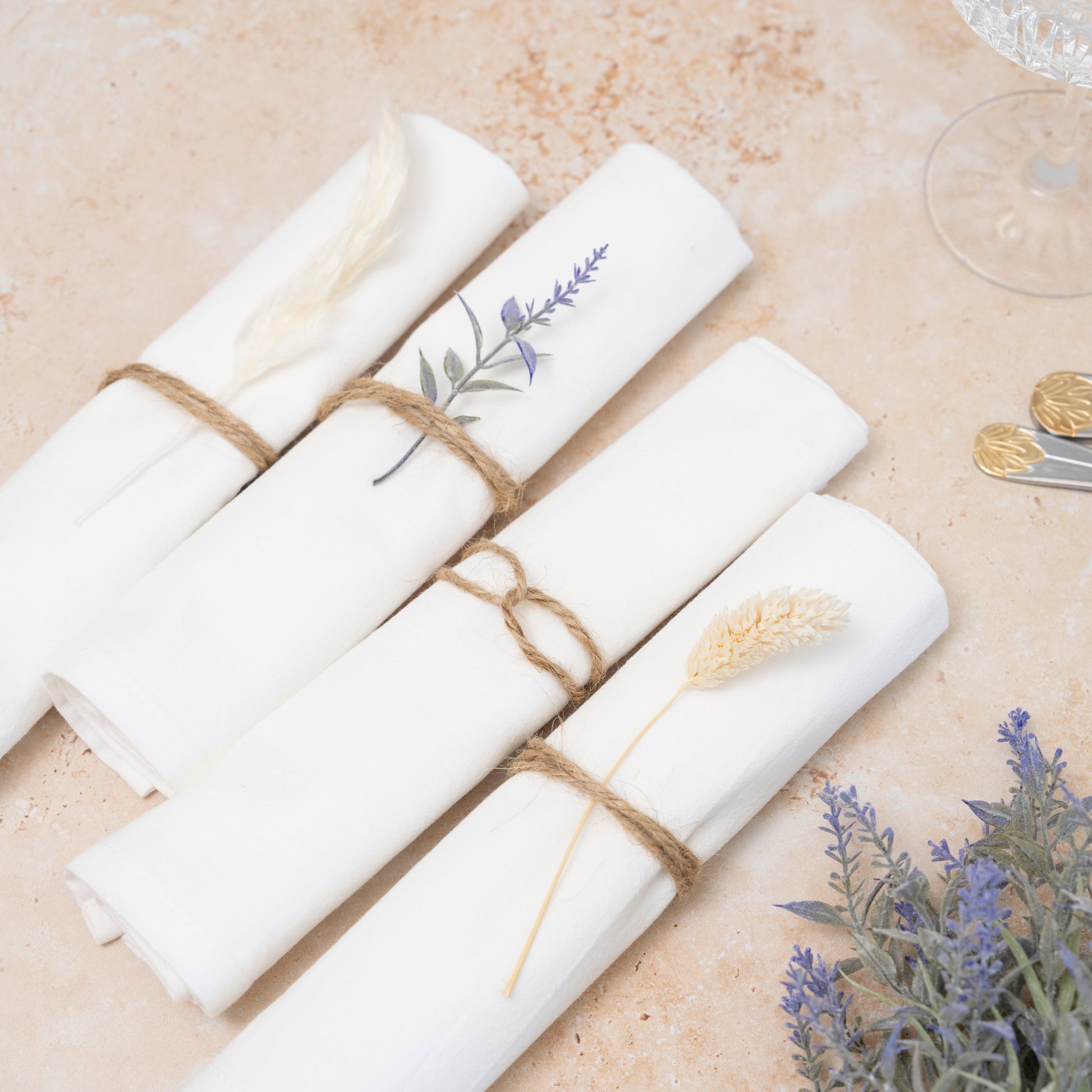 White napkins with floral designs tied with twine on a beige surface