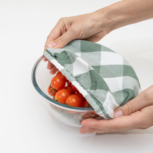 Green and white checkered cloth covering a bowl of tomatoes on a white background with plaid flax linen cloth. Elastic edge to customize bowl fit.