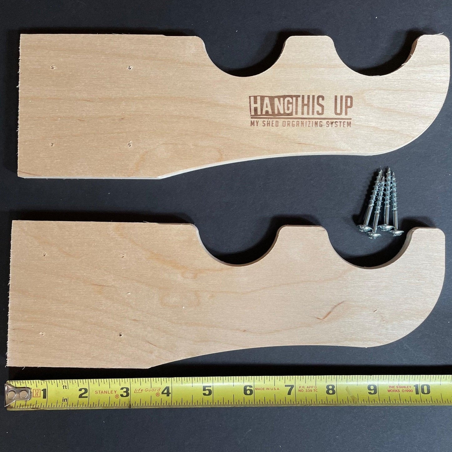 Wooden shelf bracket with screws and measurement tape on a black background