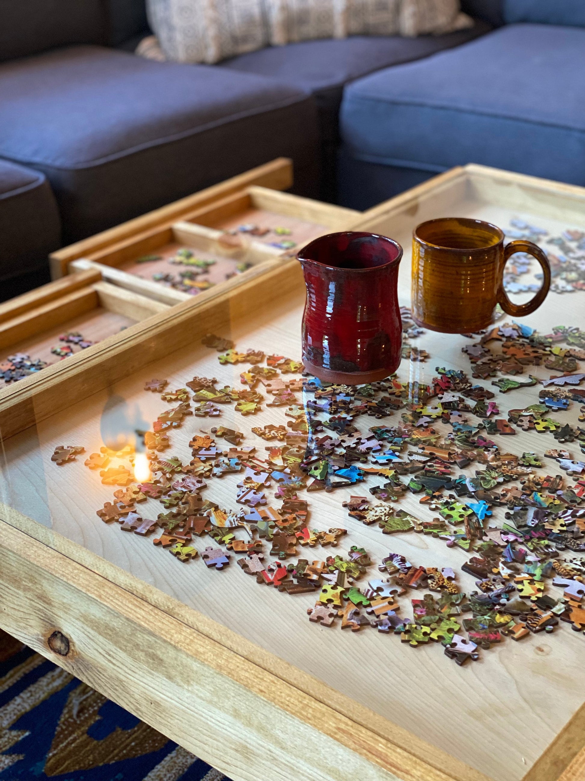 Coffee table with a puzzle and two mugs in a living room setting