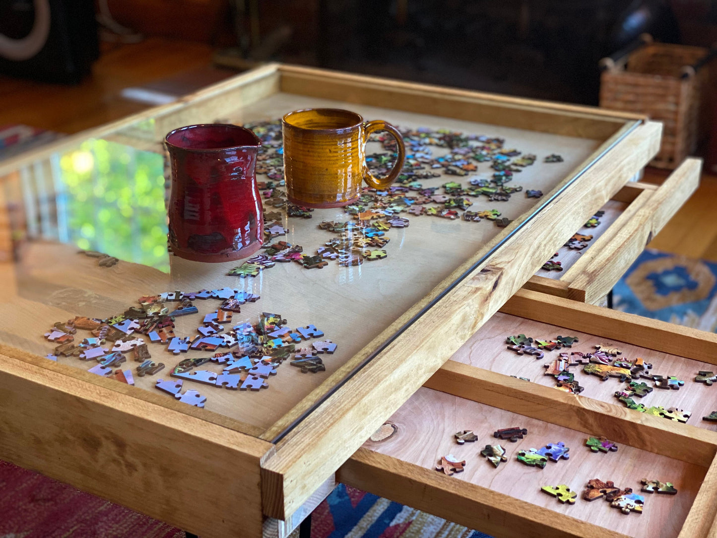 Wooden puzzle table with a partially completed puzzle and two mugs on top.