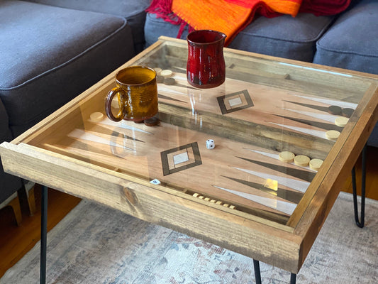 Wooden backgammon table with game pieces and mugs on a living room floor.