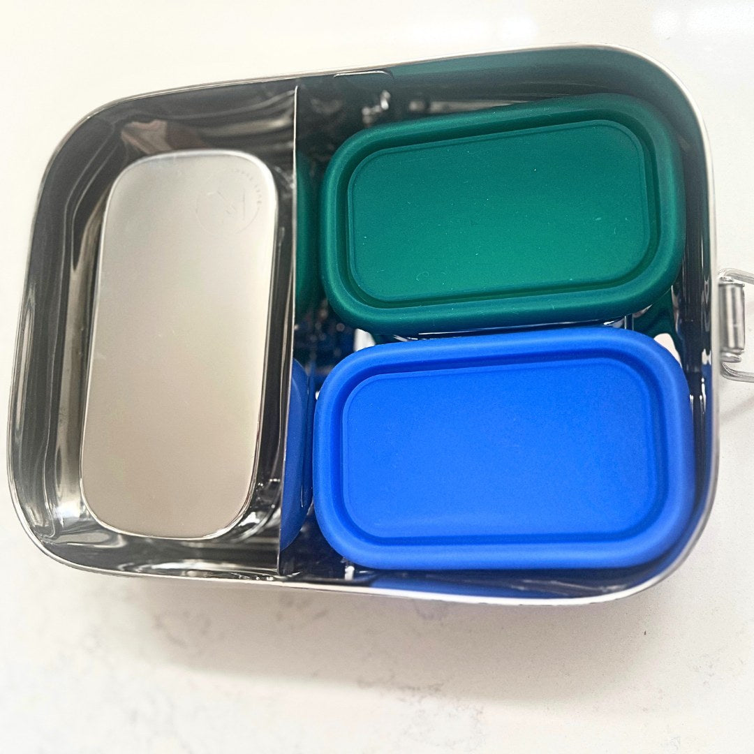 Multicolored compartmentalized container with blue, green, and silver lids on a white background